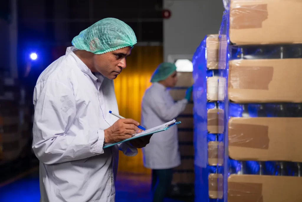 Worker inspecting food storage area with reusable thermal covers for sustainable cold chain logistics